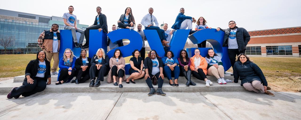 Trio Staff in front of GVSU Sign